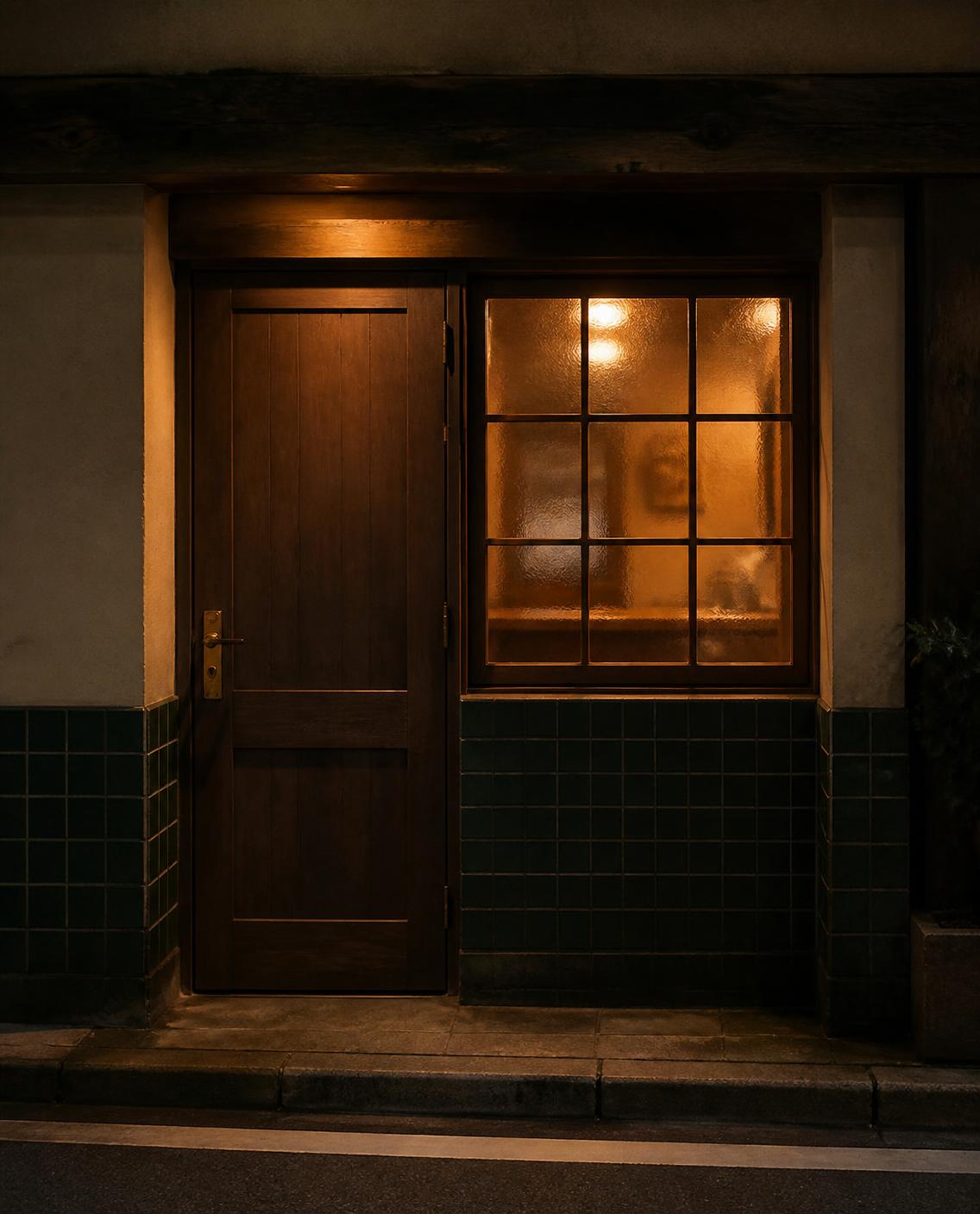 夜の店の入口。木の扉と、灯りのともった格子の窓。